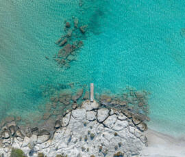 Crystal-clear water inviting you to dive, swim, and breathe. Aerial image of shallow clear water near Elafonisi with rocks and turquoise tones.