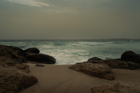 Where the sea slows down.
Falassarna, Crete. Fine art seascape photograph of Falassarna Beach in Crete, showing waves, rocks, and sandy shore under a cloudy sky.
