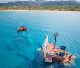 The iconic shipwreck resting in crystal-clear waters near Nopigia. Aerial photo of the Manassa Rose M shipwreck in clear turquoise water near Nopigia.
