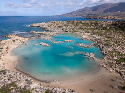 The minimalistic shoreline of White Lake Beach (Aspri Limni). Aerial view of White Lake Beach (Aspri Limni) with clear turquoise water and rocky shoreline.