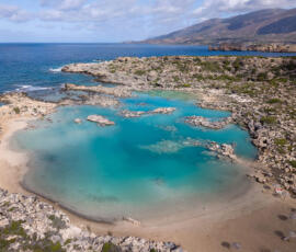 The minimalistic shoreline of White Lake Beach (Aspri Limni). Aerial view of White Lake Beach (Aspri Limni) with clear turquoise water and rocky shoreline.