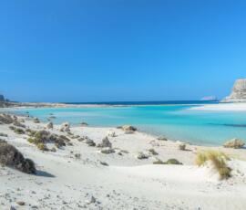 Where crystal-clear waters meet untouched white sands at the edge of Crete. Balos Lagoon in Crete with white sand, turquoise water and Gramvousa Island.